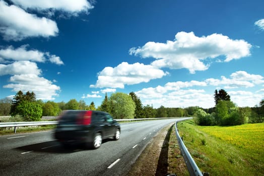 Car on asphalt road in beautiful spring day at countryside