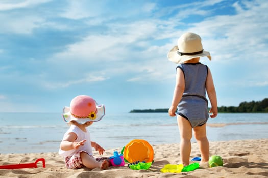 Babygirl and babyboy on the beach in straw hats