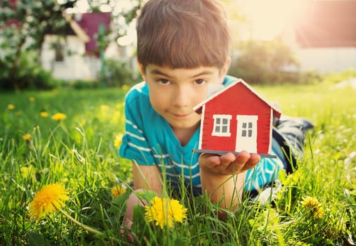 7 years old child holding red wooden model house