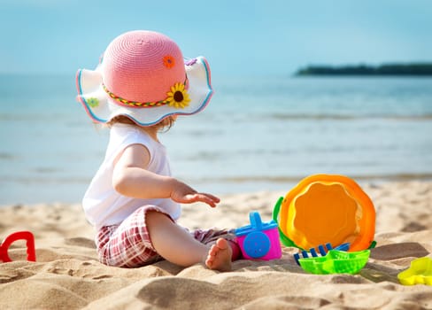 one year old girl shouting at the sea with bucket