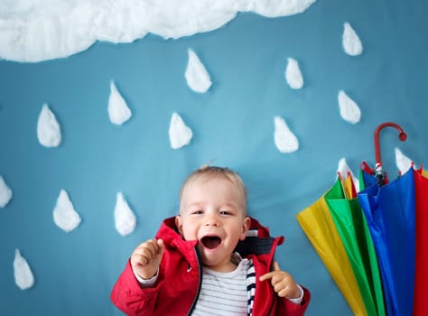 Little boy on blue background in coat with drop shapes and cloud