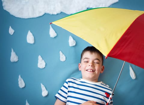 Little boy on blue background in coat with drop shapes and cloud