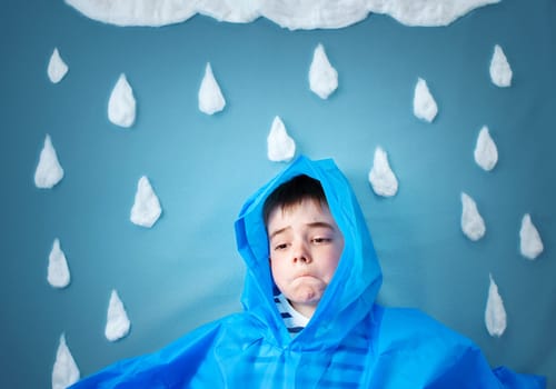 boy on blue background in coat with drop shapes and cloud