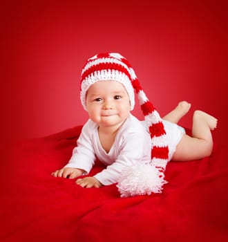little baby in knitted red whitey hat on red blanket