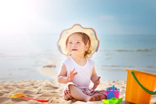 one year old girl shouting at the sea with bucket