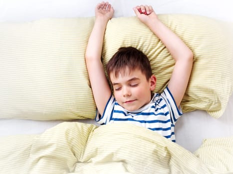 seven years old child lying in the bed with green bedding