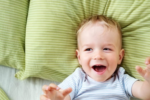 One year old baby lying in the bed with green bedding