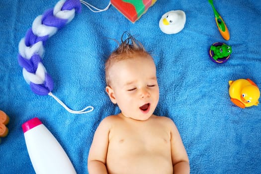 one year old baby lying on towel with washing tools