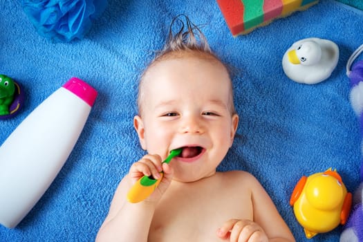 one year old baby lying on towel with washing tools