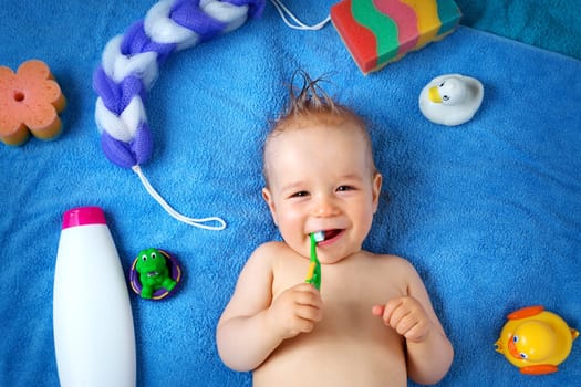 one year old baby lying on towel with washing tools
