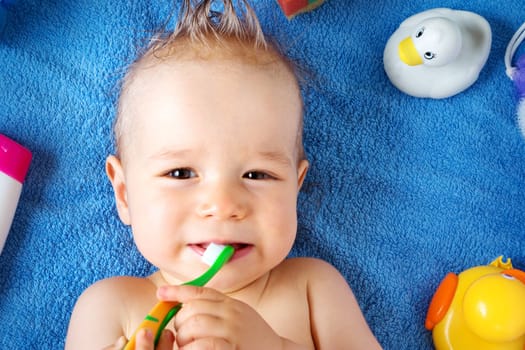 one year old baby lying on towel with washing tools