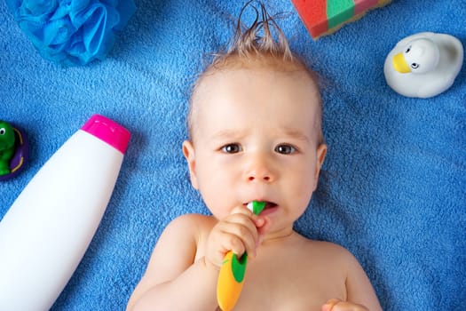one year old baby lying on towel with washing tools