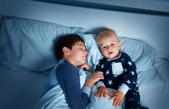 children lying in bed at night. Brothers going to sleep