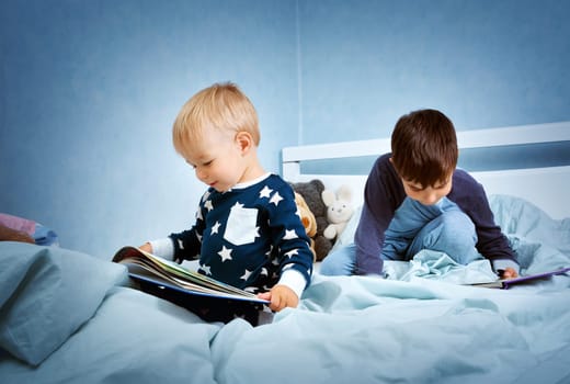 Brothers sitting in the bed in pyjamas and reading books