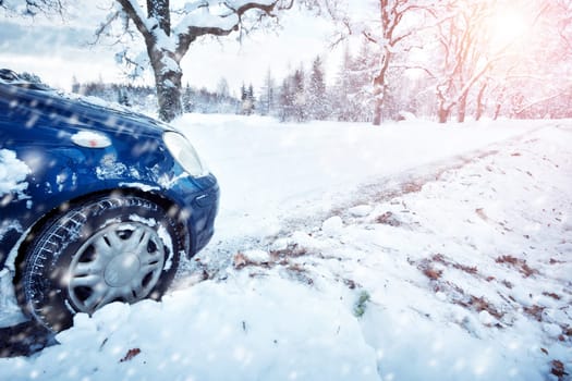Car tires on winter road covered with snow. Vehicle on snowy alley in the morning at snowfall