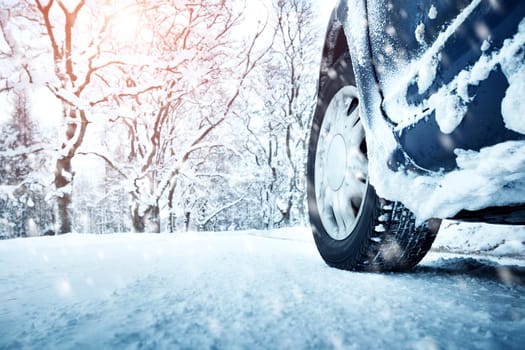 Car tires on winter road covered with snow. Vehicle on snowy alley in the morning at snowfall