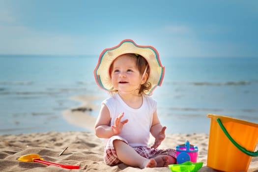 one year old girl shouting at the sea with bucket