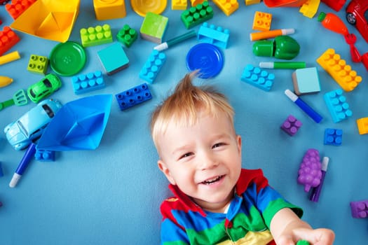 Baby boy lying on blue blanket with many toys around