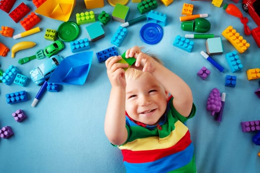 Baby boy lying on blue blanket with many toys around