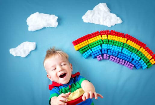 Baby boy lying on blue blanket with rainbow and clouds