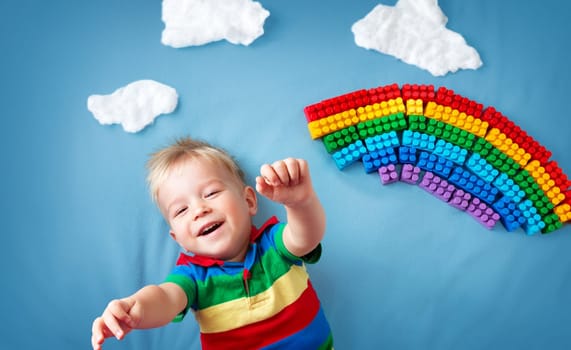 Baby boy lying on blue blanket with rainbow and clouds