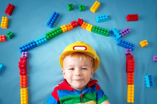 Child lying on blue blanket with blocks in house shape