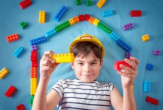 Child lying on blue blanket with blocks in house shape