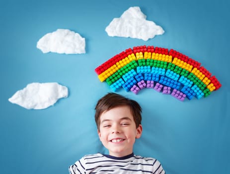 Child lying on blue blanket with rainbow and clouds