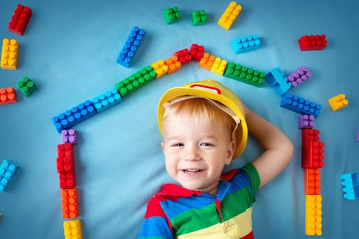 Child lying on blue blanket with blocks in house shape