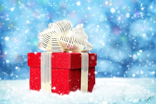 Red gift box on snow on blue background