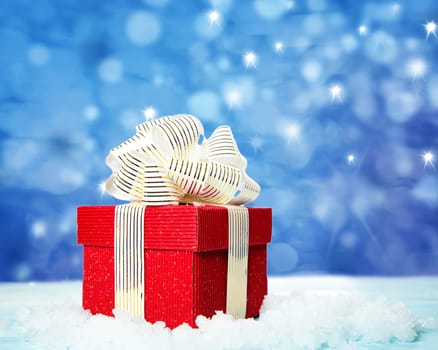 Red gift box on snow on blue background
