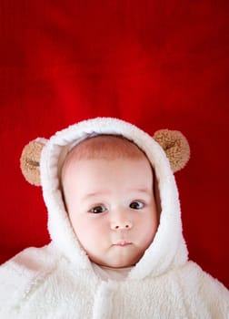 little baby in white bear costume on red blanket