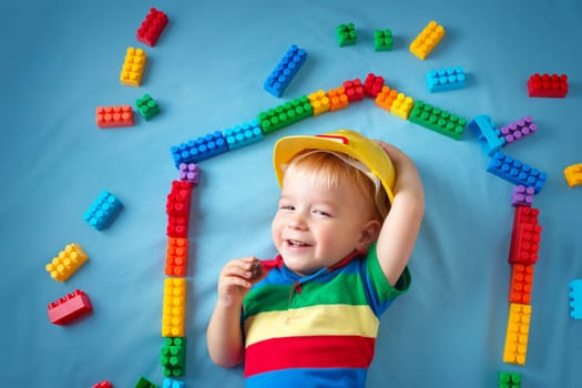 Child lying on blue blanket with blocks in house shape