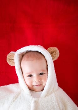 little baby in white bear costume on red blanket