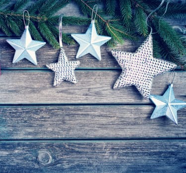 Christmas stars on wooden background with fir tree branches. Winter background
