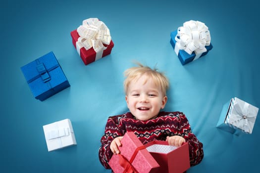Happy child on blue blanket. Cute boy with many presents