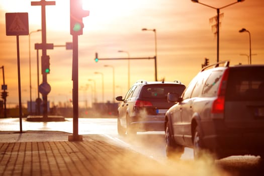 Cars moving on the road in city in early morning. View to the traffic with trafficlights and transport