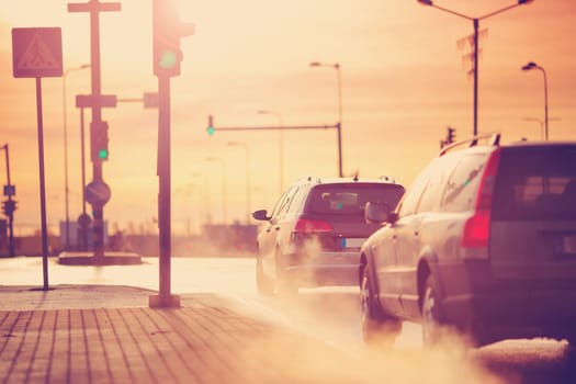 Cars moving on the road in city in early morning. View to the traffic with trafficlights and transport