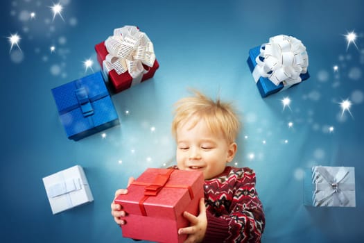 Happy child on blue blanket. Cute boy with many presents