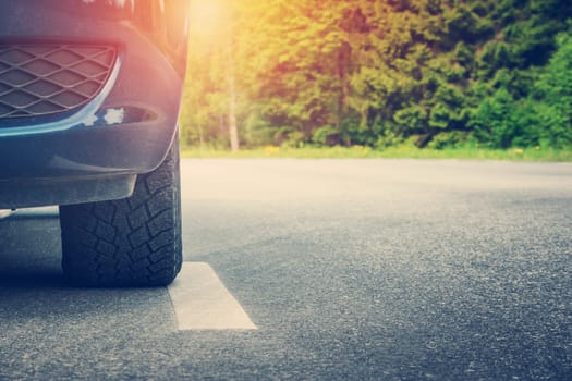 Car on asphalt road on summer day at park. Transportation panoramic background with sunlight