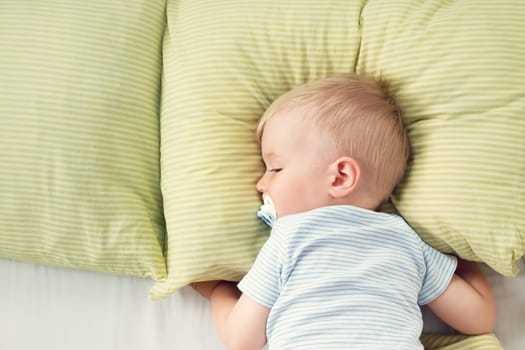 One year old baby lying in the bed with green bedding