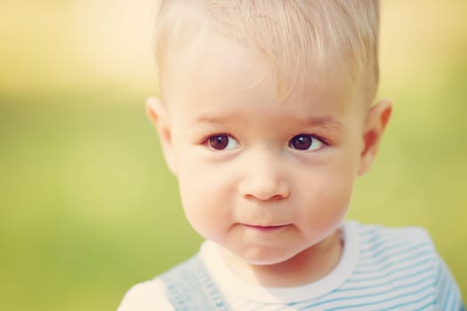 Happy little boy playing in the garden. Cute blond child portrait outdoors