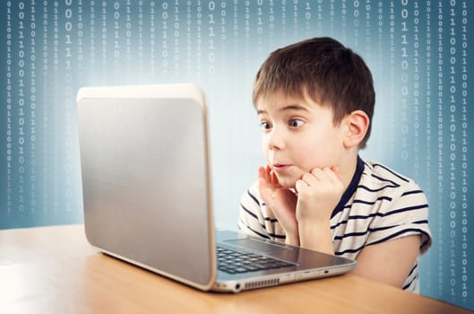 surprised seven years old child sitting with a laptop at table