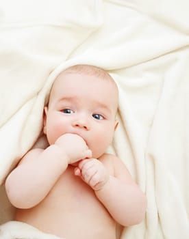 beautiful little boy lying on soft white blanket