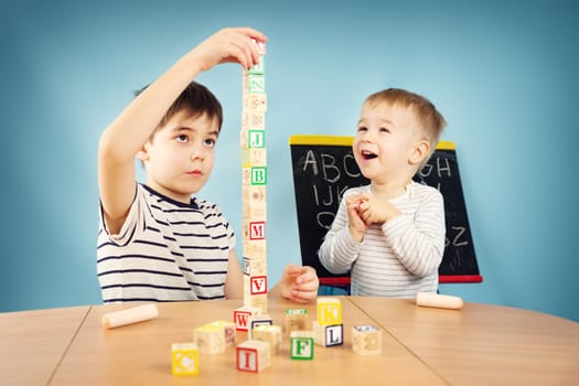 Children playing with cubes on the table. Boys studying letters