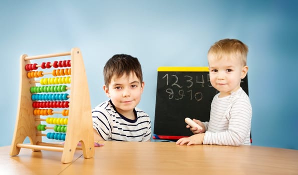 Children writing numbers on chalkboard. Boys studying