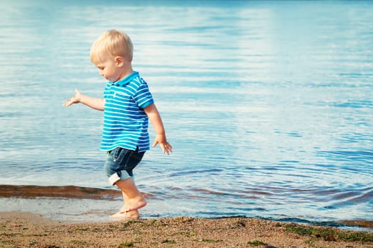boy playing on the beach. Child walking on the sea in summer