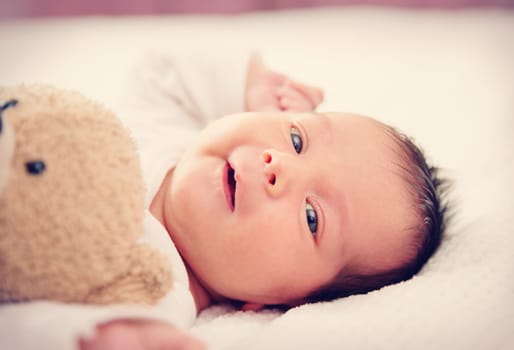Cute newborn baby girl lying in the bed. Two weeks old infant child on white soft blanket