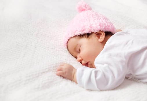 Cute newborn baby girl lying in the bed. Two month old infant child sleeping on white soft blanket