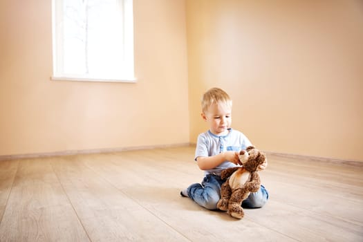 Portrait of a two years old child sitting on the floor. Pretty little boy at home